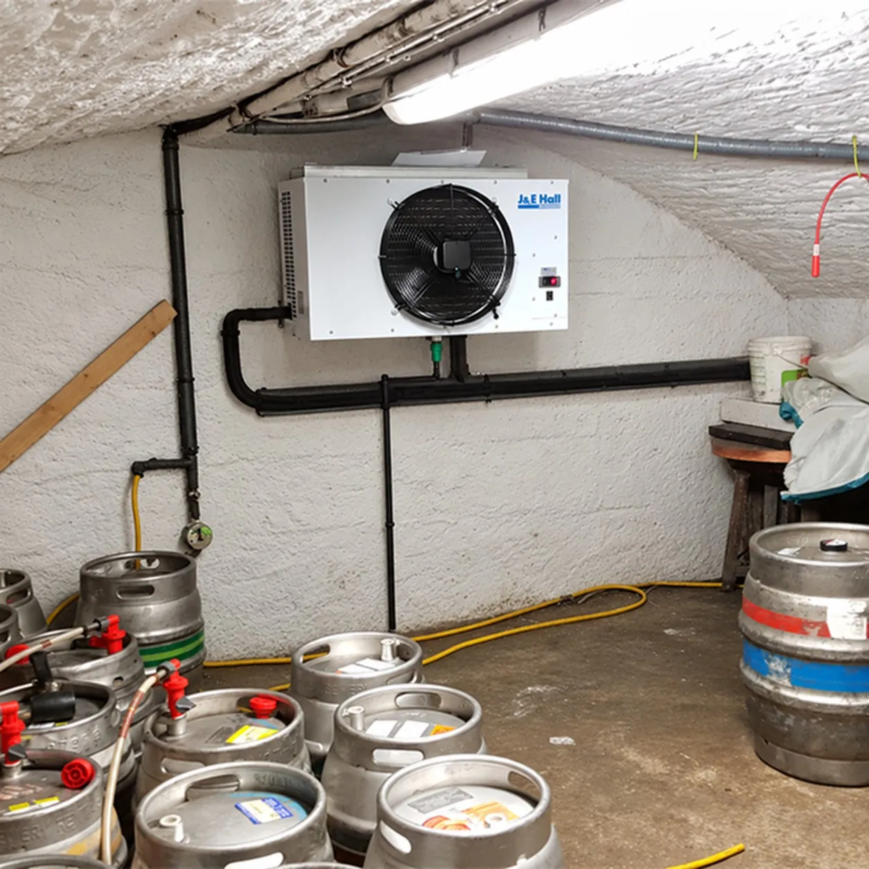 Cellar cooling unit mounted on the wall of a pub cellar above beer kegs
