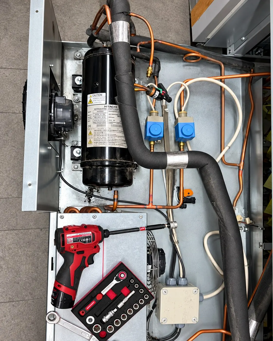 Compressor, valves and insulated pipework inside the top of a chilled cabinet