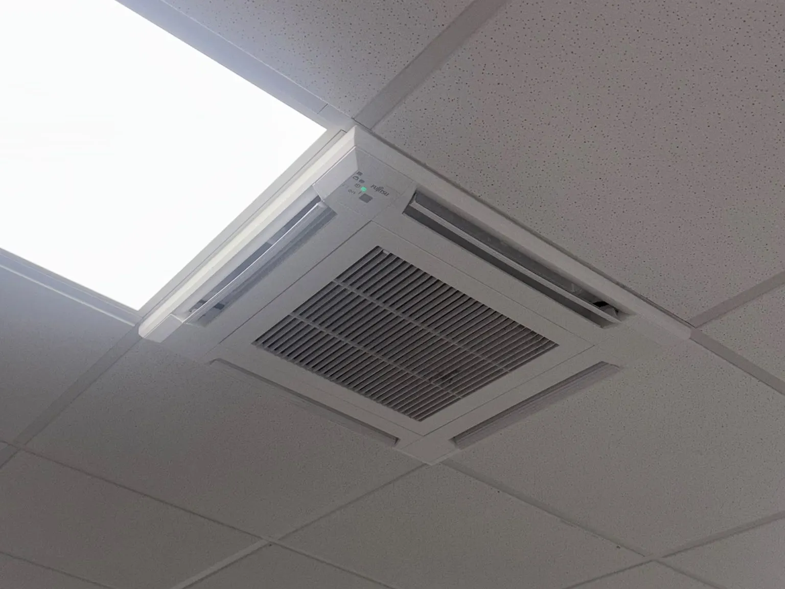 Ceiling cassette air conditioning unit set into a suspended office ceiling