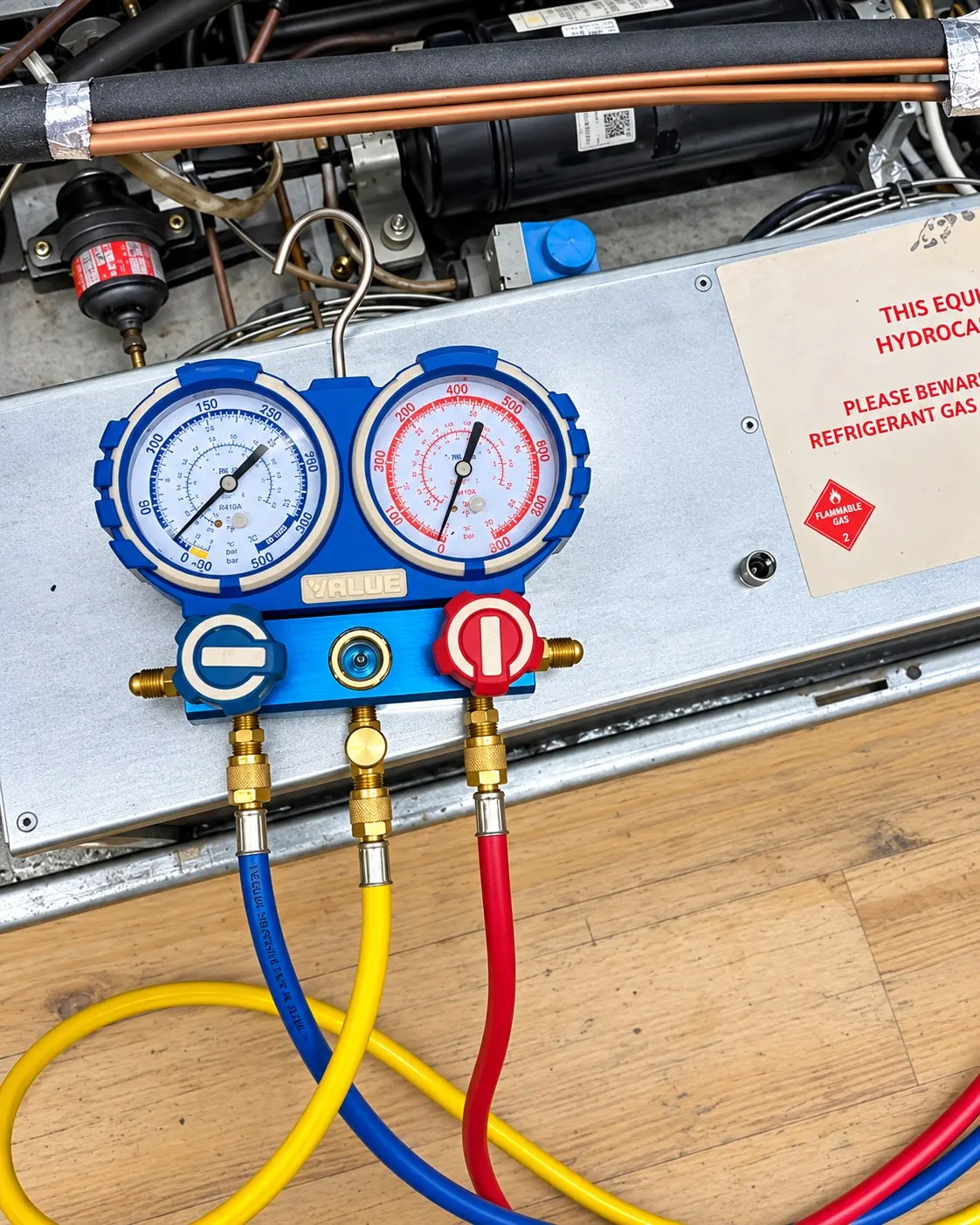 Manifold gauges connected to the system on top of a display cabinet during fault finding